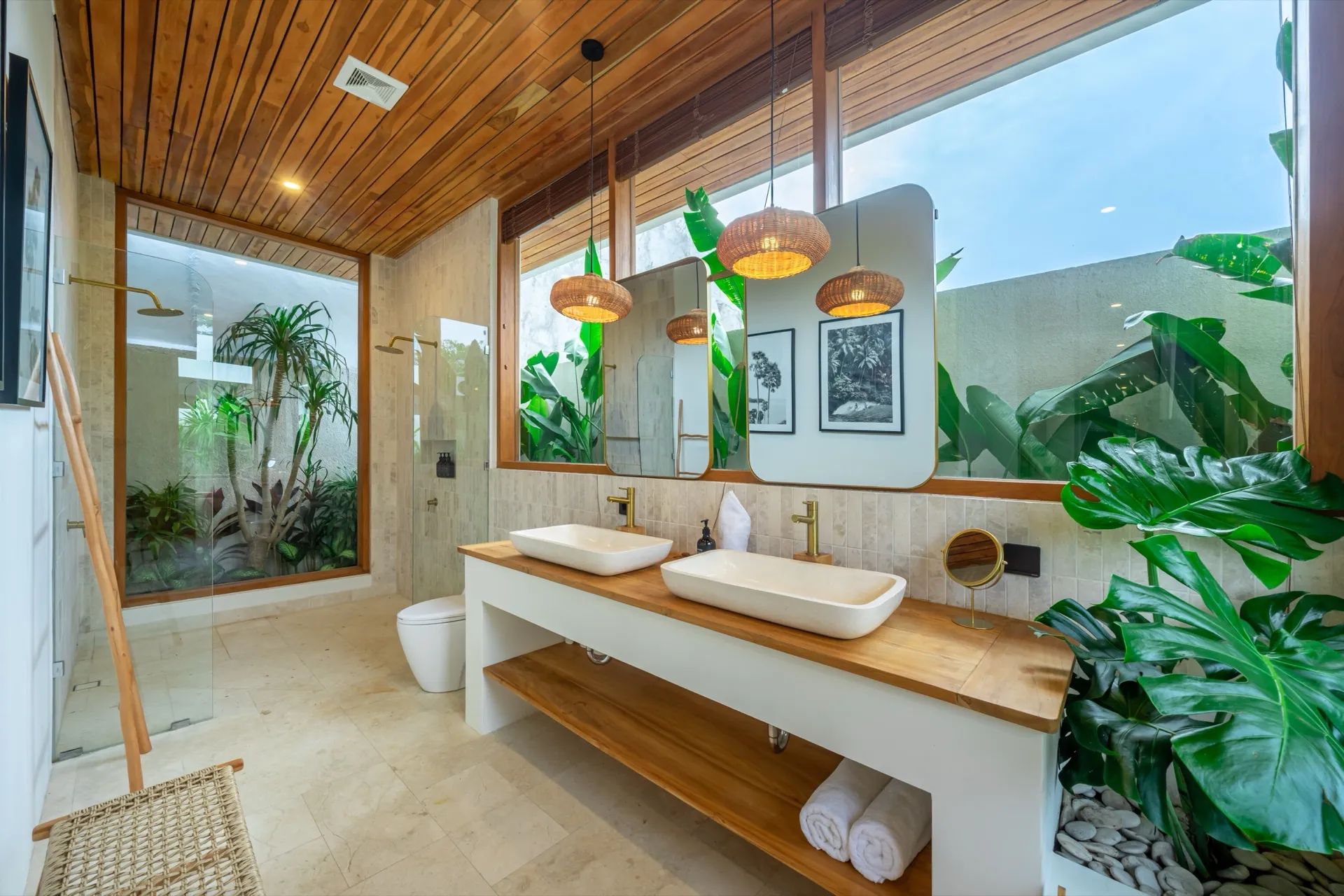 Villa Lila's bathroom with twin stone basins, brass fittings and a walk-in shower facing a planted courtyard