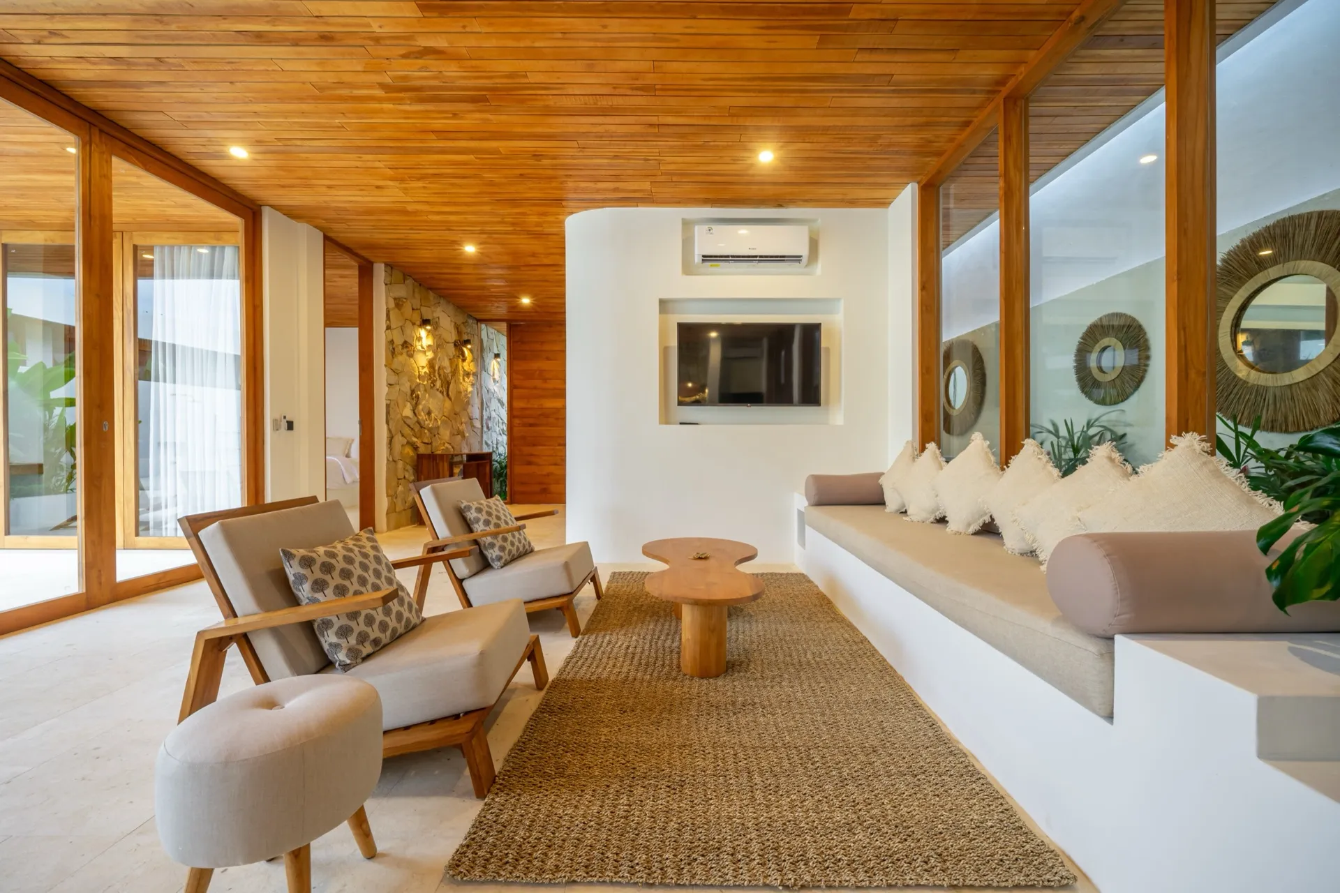 A quiet corner of Villa Lila's living room, with built-in bench seating, woven cushions and a timber ceiling