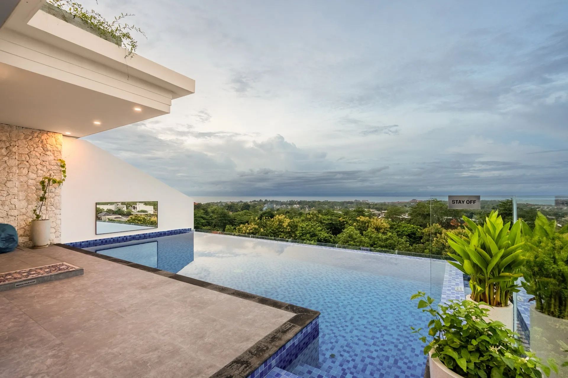 Villa Pepper's infinity pool at dusk, its edge meeting the treetops of the Bukit Peninsula with the Indian Ocean on the horizon